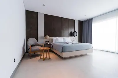 a bedroom with a king sized bed and a chair at 3 Bedroom Seminyak Apartment -3 in Seminyak