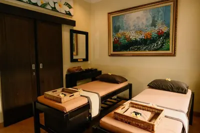 a room with three beds and a painting on the wall at Bali Orchid Spa in Kuta