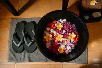 a bowl of flowers in a pan next to a pair of shoes at Bali Orchid Spa in Kuta