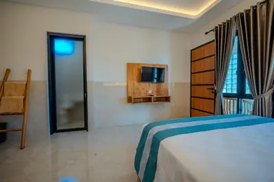a bedroom with a bed and a tv on a wall at Wana Kubu Suite and Dormitory in Ngurah Rai International Airport