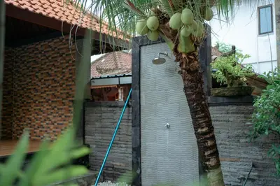 a hose hooked up to a house with a palm tree at Wana Kubu Suite and Dormitory in Ngurah Rai International Airport
