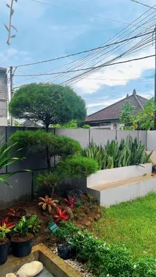 a backyard with a garden with plants and a fence at Batara Room in Nusa Dua