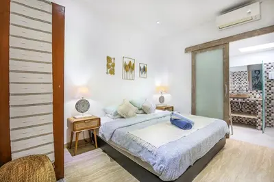 a bedroom with a bed and a table with a chair at Legian Beach Villa - 3-room open villa, private pool, near the beach, Netflix in Legian