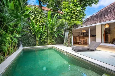a pool with a chair next to a house at Legian Beach Villa - 3-room open villa, private pool, near the beach, Netflix in Legian