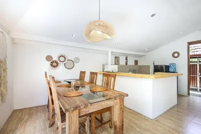 a kitchen and dining room with a wooden table and chairs at Legian Beach Villa - 3-room open villa, private pool, near the beach, Netflix in Legian