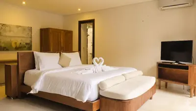 a bedroom with a large bed and a television at Calladi Villa in Seminyak