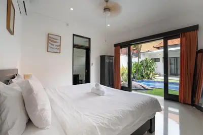 a bedroom with a white bed and a large window at Homy 3 Bedrooms Villas in Canggu Umalas in Kerobokan
