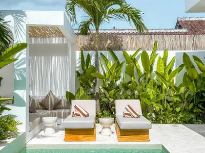 a patio with two white chairs and plants at Villa Nabu - Serene Tropical Escape in Heart of Seminyak in Seminyak