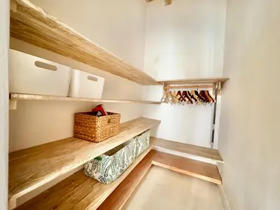 a walk in closet with wooden shelves and a basket at Casa Bali in Kerobokan
