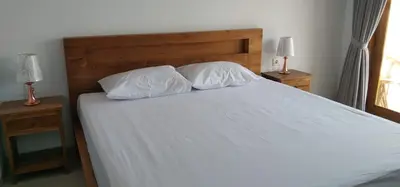 a bed with two white pillows and two lamps at wiratijenengguesthouse in Kerobokan