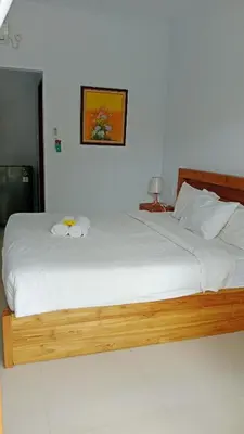 a bedroom with a large bed with white sheets at wiratijenengguesthouse in Kerobokan