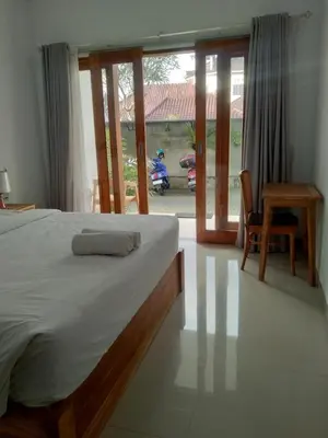 a bedroom with a bed and a sliding glass door at wiratijenengguesthouse in Kerobokan