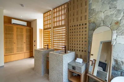 a bathroom with two sinks and a stone wall at Villa Twin 1 by BaliSuperHost in Seminyak