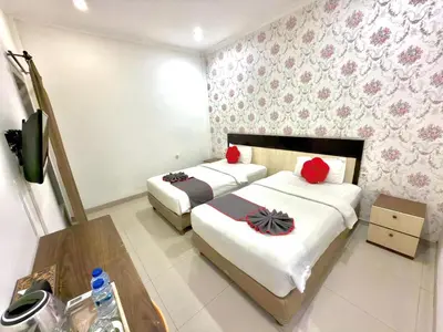 a bedroom with two beds with red pillows at Famora Stay Kuta Bali in Ngurah Rai International Airport
