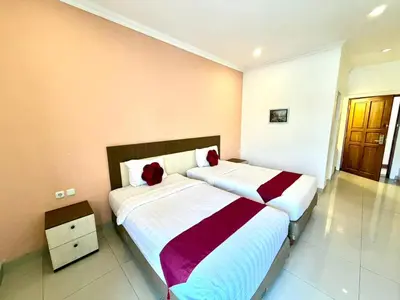 a bedroom with two beds with red pillows at Famora Stay Kuta Bali in Ngurah Rai International Airport