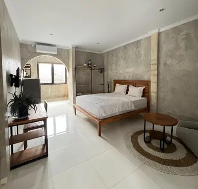 a bedroom with a bed and a table and a couch at ET Living Cozy Studio Room in Kerobokan