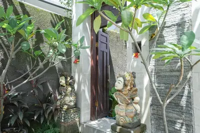 two statues standing in front of a door with plants at Lumbung Sari Studio in Ngurah Rai International Airport