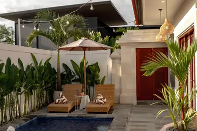 a patio with chairs and an umbrella next to a pool at A Better Villa 3BR Seminyak 5min Beach Bintang in Seminyak