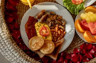 a plate of breakfast food with eggs bacon beans and fruit at A Better Villa 3BR Seminyak 5min Beach Bintang in Seminyak