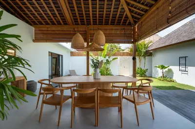 an outdoor dining room with a wooden table and chairs at Villa Nador Seminyak in Seminyak