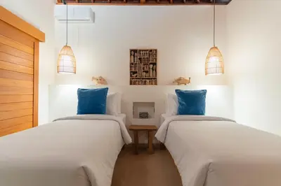 two beds in a white room with blue pillows at Villa Nador Seminyak in Seminyak