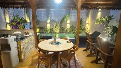 a dining room with a table and some plants at Joglo Raera Bali in Seminyak