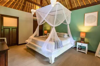 a bedroom with a bed with a mosquito net at Calinda Tropical 1 BR Bungalow With Garden View in Seminyak