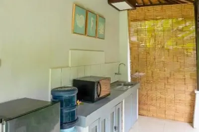 a kitchen with a counter top with a microwave at Calinda Tropical 1 BR Bungalow With Garden View in Seminyak