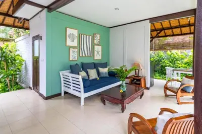 a living room with a blue couch and a table at Calinda Tropical 1 BR Bungalow With Garden View in Seminyak