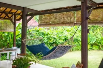 a hammock on a patio with a garden at Calinda Tropical 1 BR Bungalow With Garden View in Seminyak