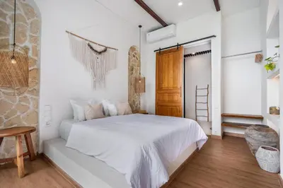 a bedroom with a white bed and a wooden floor at Palm Sugar Villa - Stylish 3BR Retreat with Pool in Jimbaran