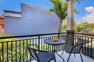 a table and chairs on a balcony with a palm tree at Ondio Villa in Seminyak