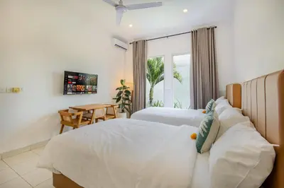 a bedroom with two beds and a table and a window at Ondio Villa in Seminyak