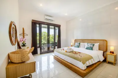 a bedroom with a large bed and a balcony at Ondio Villa in Seminyak