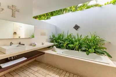 a bathroom with a tub and a sink and plants at Gahyaka Comfortable 2 BR Deluxe Private Pool Villa in Seminyak