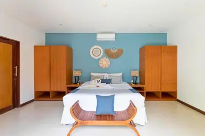 a bedroom with a large bed with a blue wall at Gahyaka Comfortable 2 BR Deluxe Private Pool Villa in Seminyak