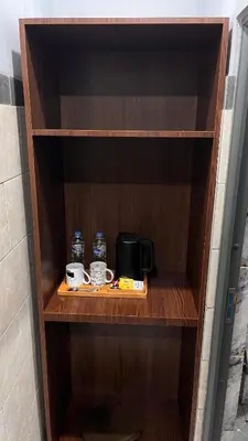 a wooden shelf with a coffee maker and cups on it at Tirta Suci Guest House in Ngurah Rai International Airport