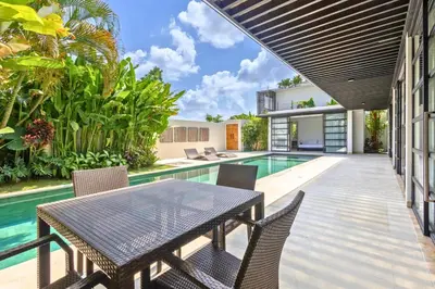 an outdoor patio with a table and chairs next to a swimming pool at Zen Retreat 3BR Japanese Inspired Oasis with Pool in Canggu