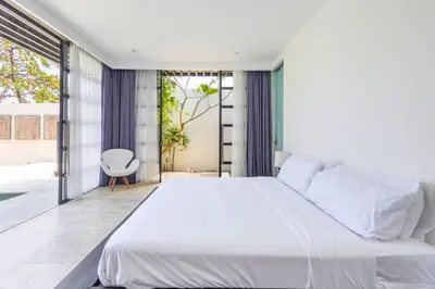 a bedroom with a large white bed and a chair at Zen Retreat 3BR Japanese Inspired Oasis with Pool in Canggu