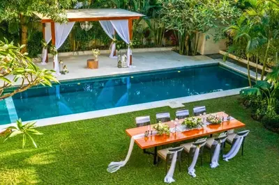a table and chairs in front of a swimming pool at Kalyca Stunning 5 BR Private Pool Villa in Jimbaran