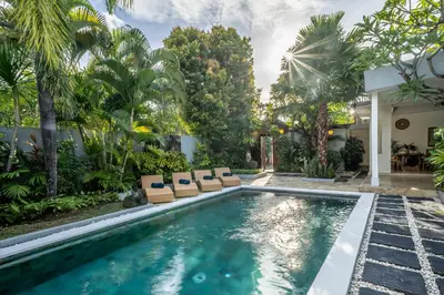 a swimming pool with lounge chairs and a house at Villa Melbourne in Seminyak