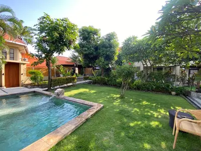 a backyard with a swimming pool and a grass yard at arjuna house in Seminyak