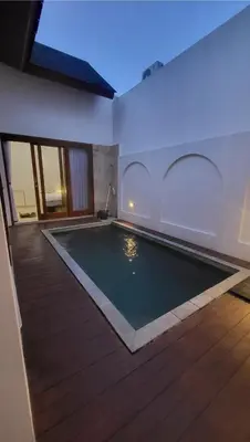 a swimming pool in a house with a wooden floor at Angeliq Villa Nusa Dua Bali in Nusa Dua