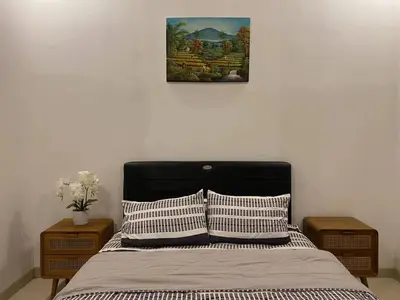 a bedroom with a bed with two tables and a picture on the wall at Angeliq Villa Nusa Dua Bali in Nusa Dua