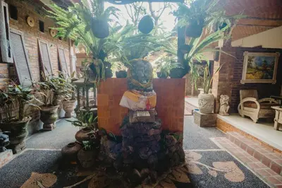 a statue in the middle of a room with plants at Samblung Mas House in Denpasar