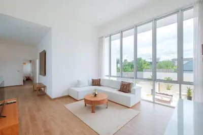 a living room with a white couch and large windows at Villa Turkuaz in Seminyak