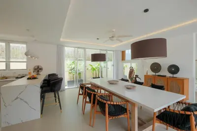 a kitchen with a white counter top and a table and chairs at Villa Turkuaz in Seminyak