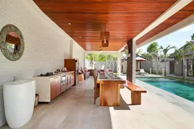 a kitchen and living room with a table and a pool at Deanda Elegant 4 BR Private Pool Villa in Jimbaran