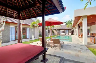 a patio with an umbrella and a swimming pool at Deanda Elegant 4 BR Private Pool Villa in Jimbaran