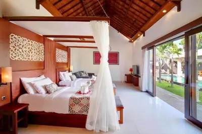 a bedroom with a bed with a curtain in it at Deanda Elegant 4 BR Private Pool Villa in Jimbaran